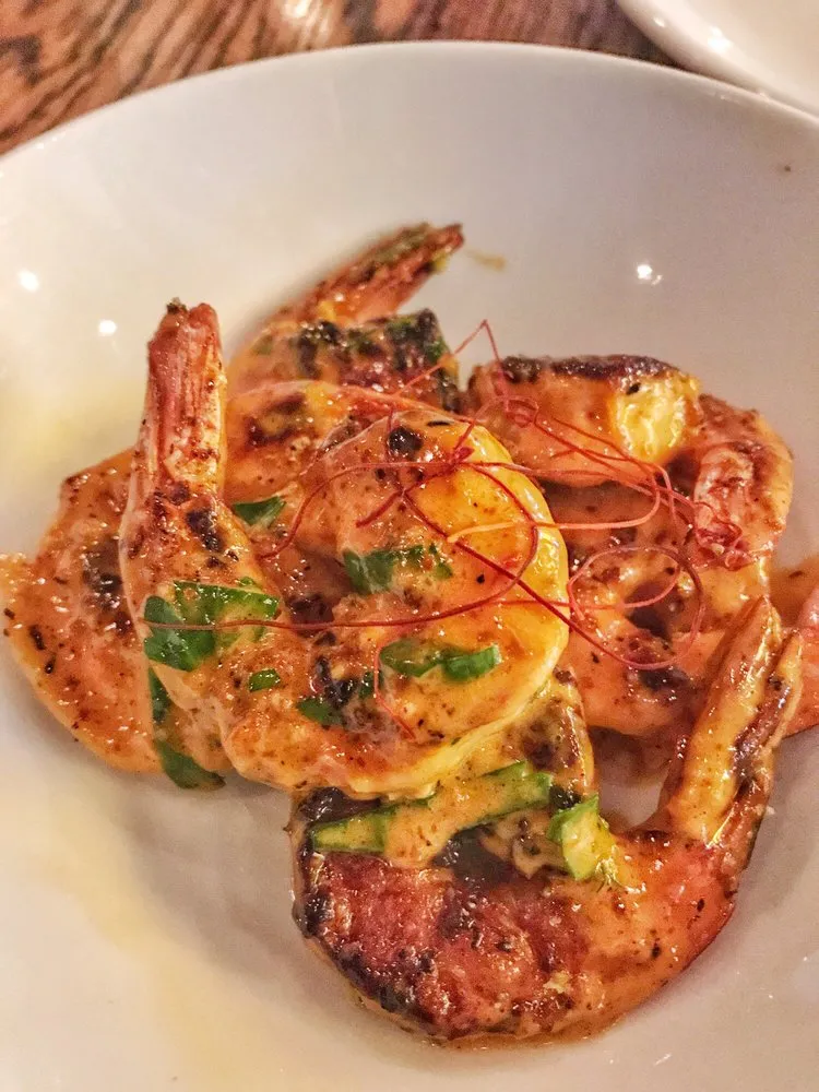 Garlic shrimp at Toro, seared shrimp with their tails on in a creamy orange sauce with chopped green herbs and fine threads of red chili, in a white bowl