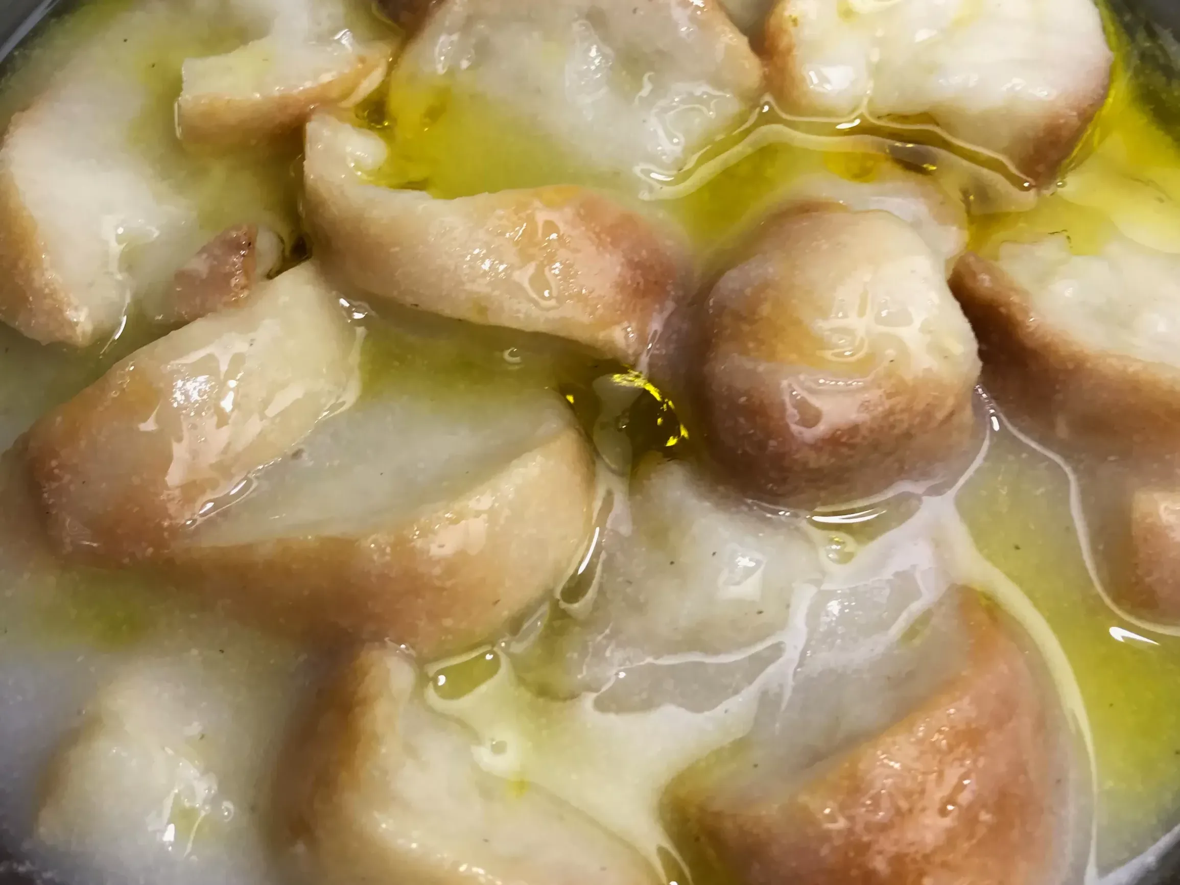 Trahana poured over chunks of bread in a bowl, with olive oil on top