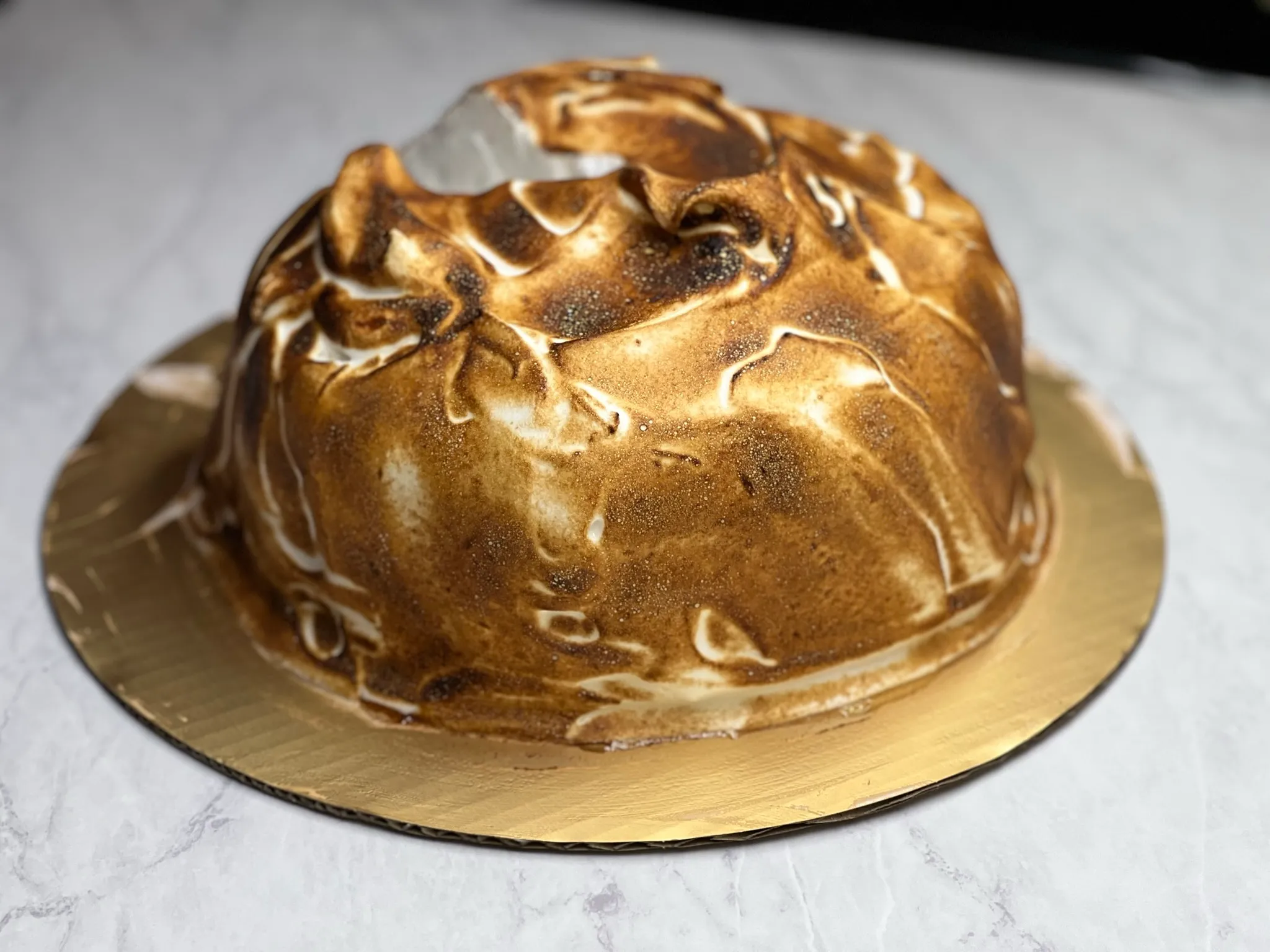 The Cipriani meringue cake, a dome of torched Italian meringue on a gold cake board