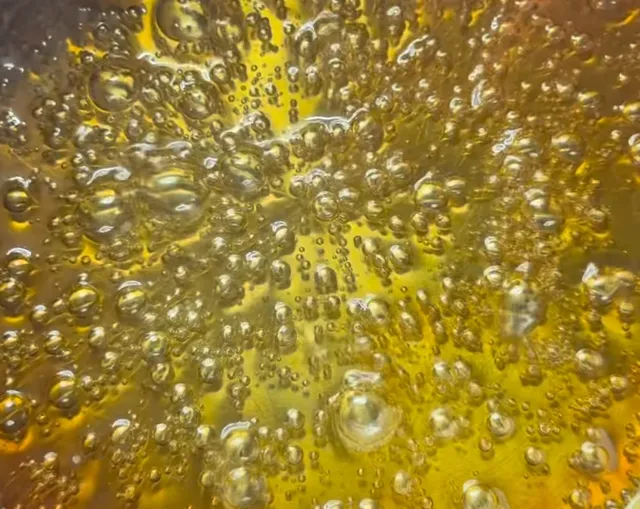 Sugar and water bubbling in a saucepan, just starting to turn golden
