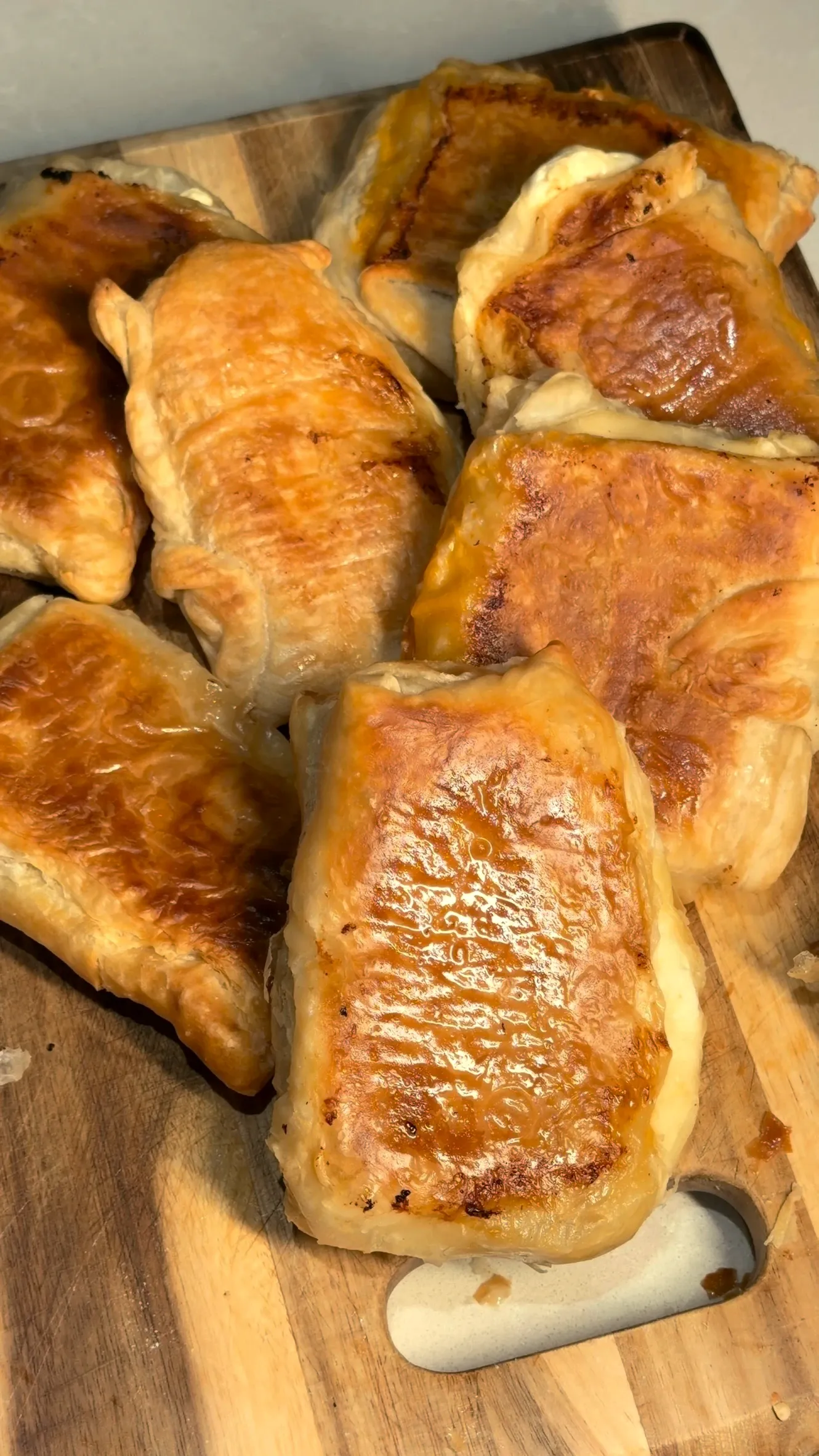 Square byrek with cheese, browned on top, piled on a wooden board