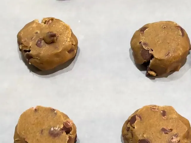 Frozen balls of chocolate chip cookie dough spaced out on parchment paper