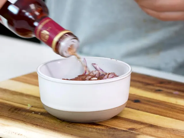 Red wine vinegar poured over sliced red onion covered in sumac, in a small white bowl