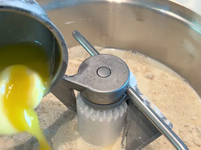 Melted butter pouring into the stand mixer bowl, over the flour and the milk