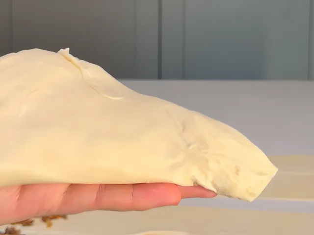A folded raw byrek triangle resting on an open hand