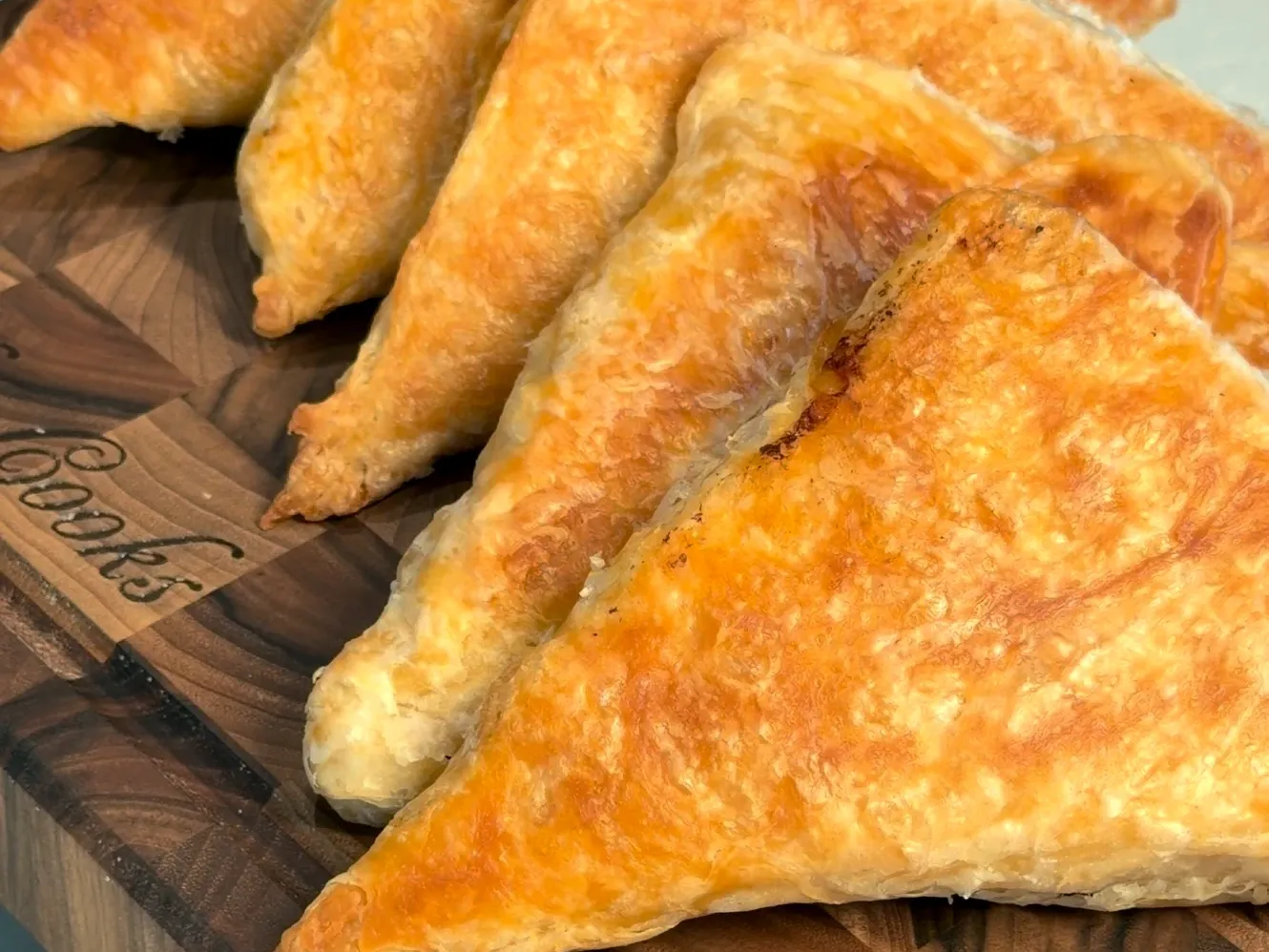 Golden, flaky byrek triangles lined up on a wooden board