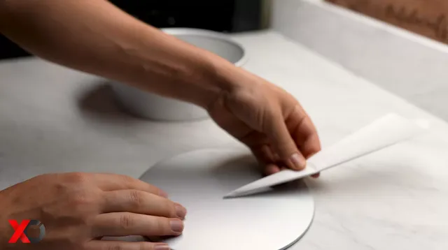 Folding parchment paper into a narrow triangle to cut a circle for the pan