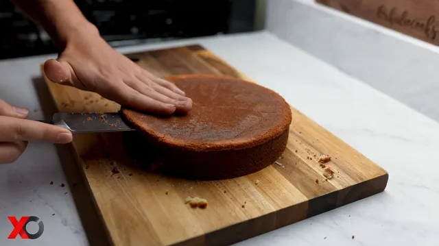 Slicing a baked cake horizontally with a big knife on a wooden board