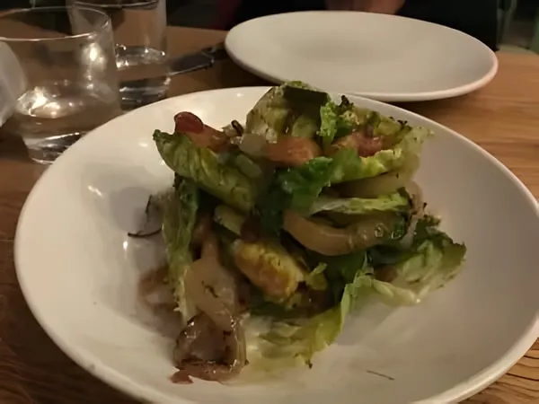 Warm lettuce hearts with soft cooked onions in a white bowl