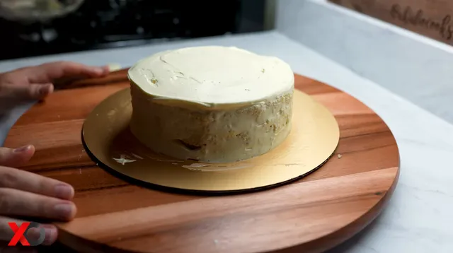 The three layers stacked and frosted on a gold cake board, ready for the meringue