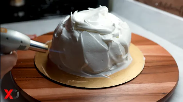 Torching the Italian meringue on the cake with a kitchen torch