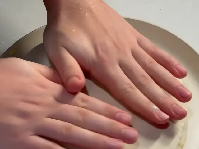Two hands pressing the last, unbuttered sheet onto the stack of buttered sheets