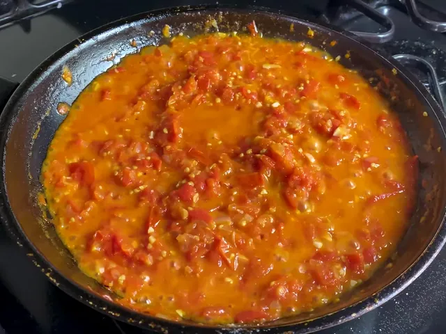 The tomato sauce after about 20 minutes in the frying pan, thick and orange-red, with soft pieces of tomato, onion and garlic